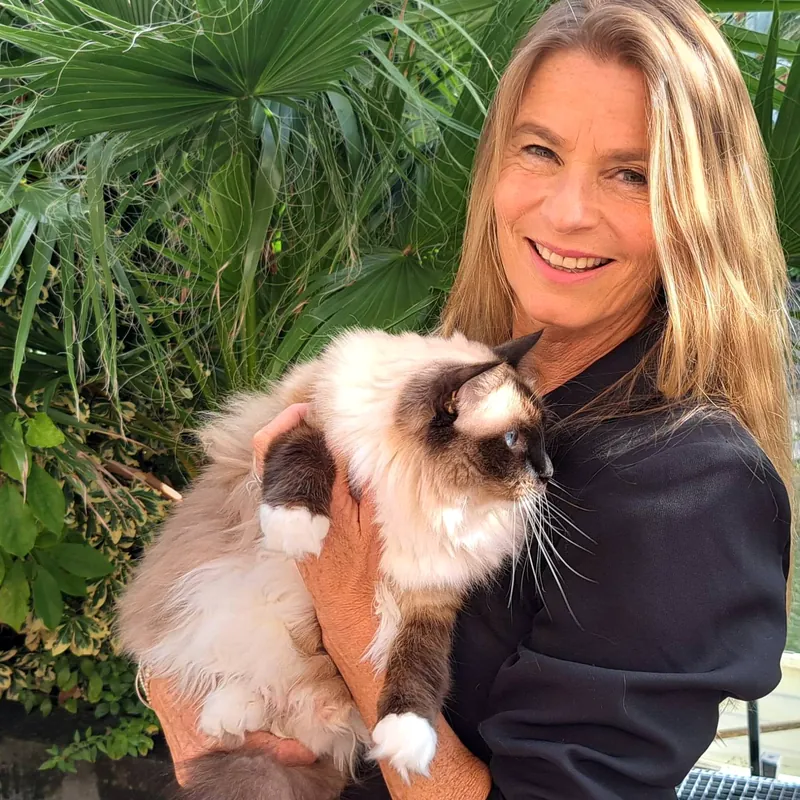 Marjan, de Kattenmadam, lachend met een kat op haar arm